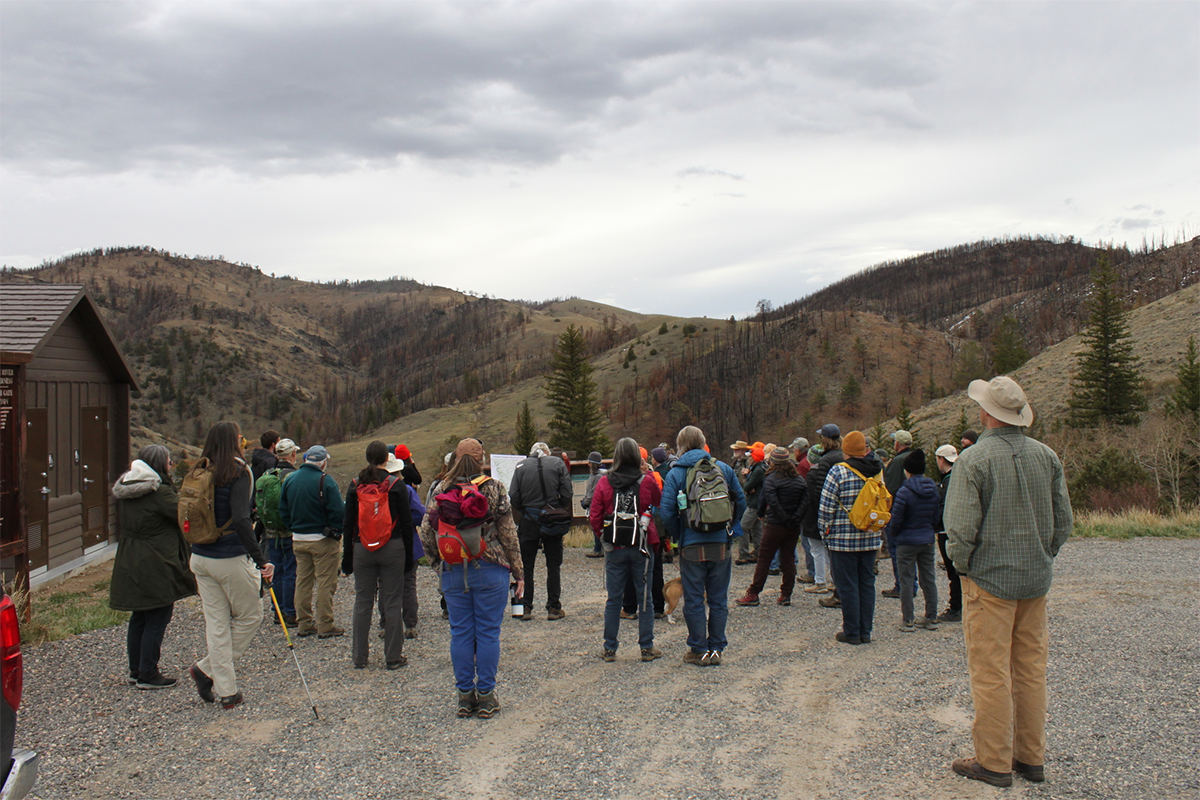A photos of the Mullen Fire hiking group watching a presentation at the 6-mile campground.