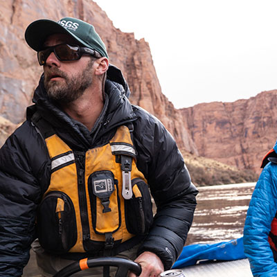 A photo of Morgan Ford navigating a raft upstream on a river. 