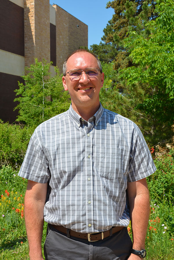 Image of Brent E. Ewers standing in his front yard.